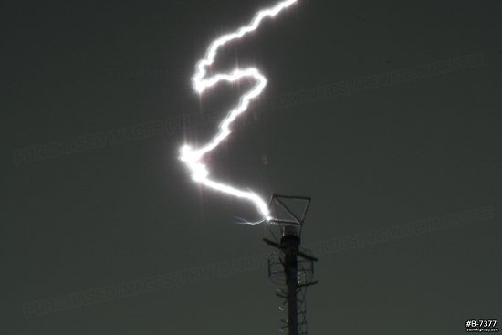 Extreme close-up of lightning striking a tower, with upward leaders visible.