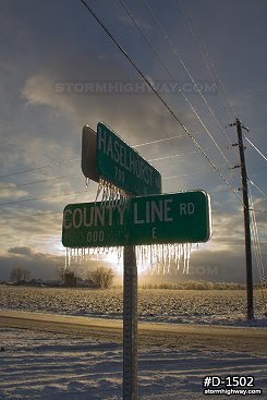 Sunlit thick icicles on street signs after an ice storm, vertical
