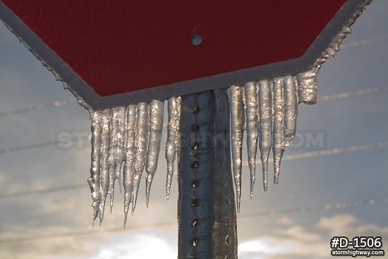 Sunlit thick icicles on stop sign after an ice storm