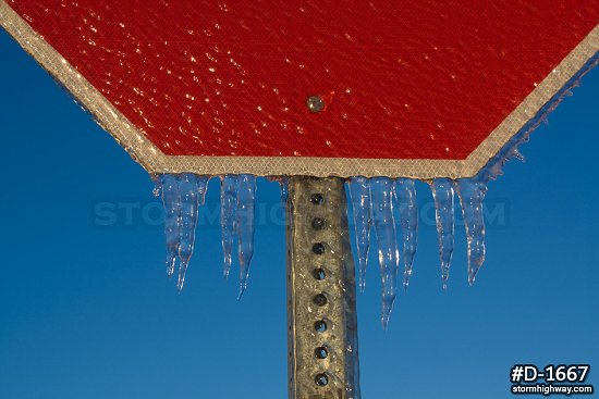 Heavy ice coating a stop sign with blue sky after an ice storm