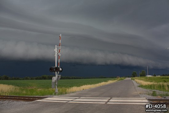 Dark severe thunderstorm clouds approaching railroad crossing