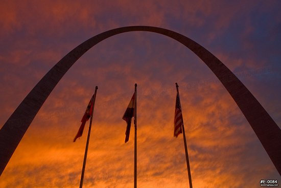 A colorful sunset over the Gateway Arch with flags in St. Louis