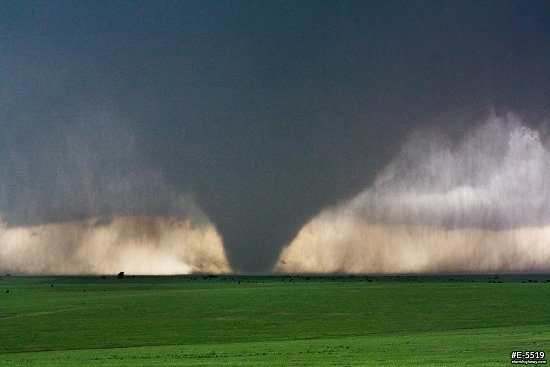 A large, dark cone tornado looms over green Kansas prairie near the town of Bennington
