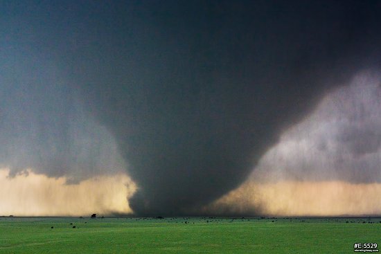 A large, strong and violent EF4 tornado looms over green Kansas prairie near the town of Bennington