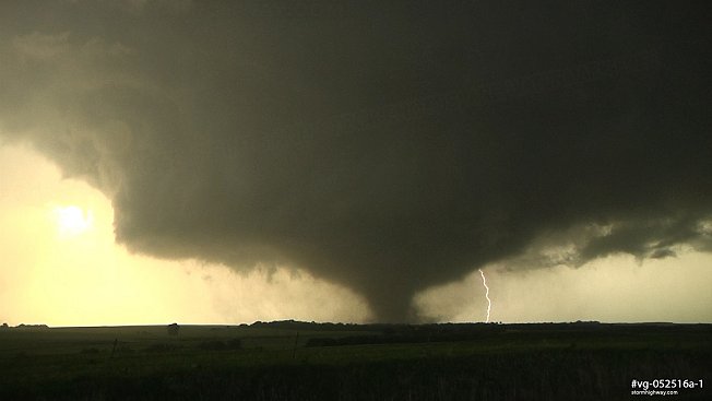 A long-lived EF4 tornado passes near Abilene, Kansas with the sun shining and lightning